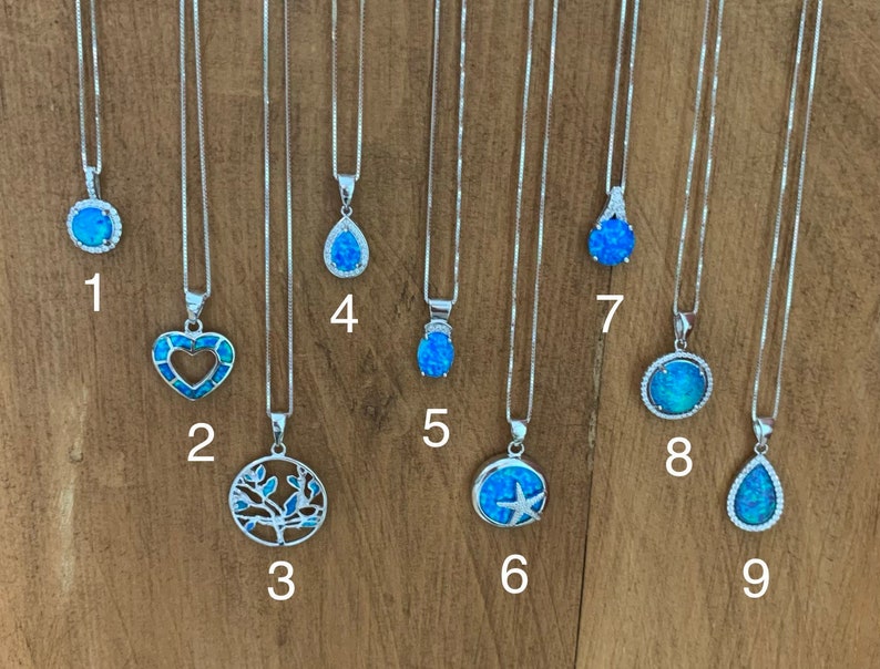May include: Nine silver necklaces with blue opal pendants. The pendants feature different designs, including a circle, heart, tree, teardrop, star, and starfish.