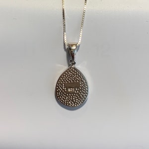 May include: Silver teardrop pendant necklace with a textured back and the inscription "925" on the back.
