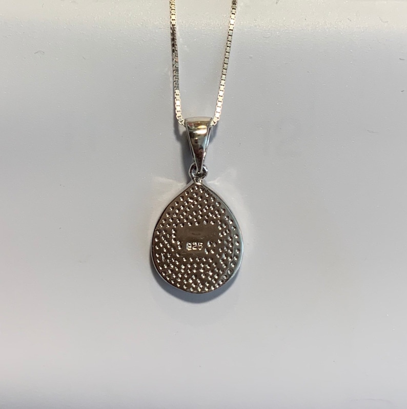 May include: Silver teardrop pendant necklace with a textured back and the inscription "925" on the back.