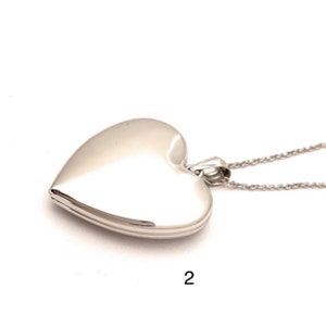 May include: Silver heart-shaped locket necklace with a delicate chain. The locket is open and ready to hold a photo or small memento.