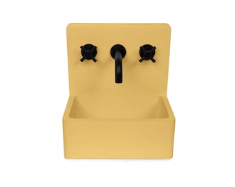 Puede incluir: Un lavabo de pared de hormigón amarillo con un grifo negro y dos pomos negros.