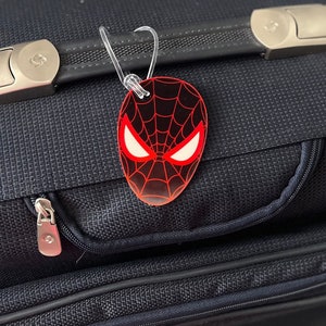 May include: A black suitcase with a red and black Spider-Man luggage tag attached to the handle.