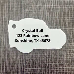 May include: White car-shaped tag with black text that reads "Crystal Ball 123 Rainbow Lane Sunshine, TX 45678"