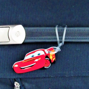 May include: A blue suitcase with a silver buckle and a red Lightning McQueen luggage tag.