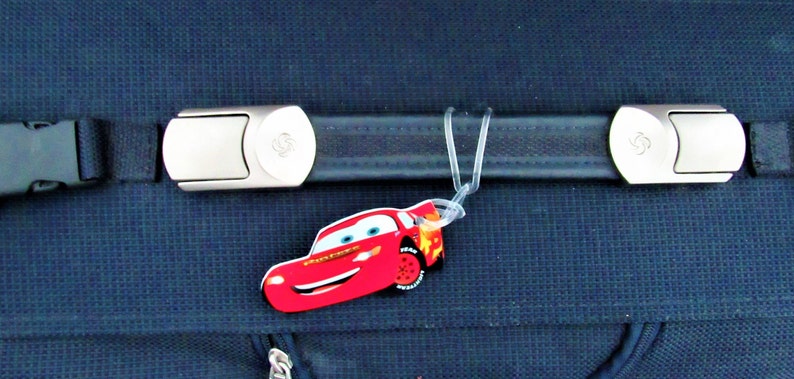 May include: A blue suitcase with a silver buckle and a red Lightning McQueen luggage tag.