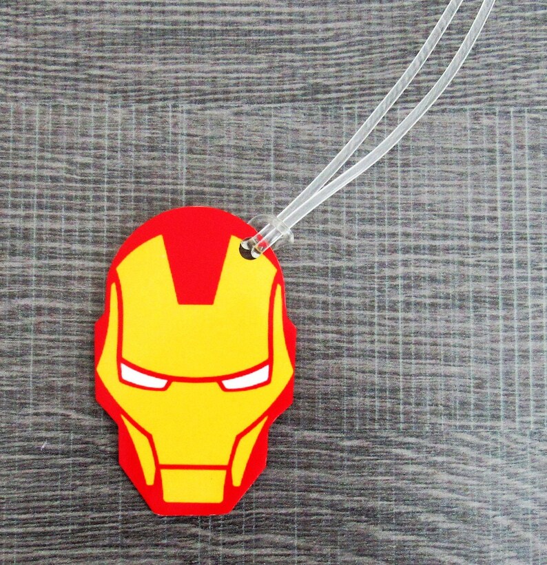 Puede incluir: Etiqueta de equipaje roja y amarilla con una imagen de dibujos animados de la cara de Iron Man.
