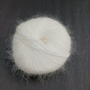 May include: A ball of white yarn, tightly wound with a soft, fuzzy texture. The yarn appears to be made of a delicate fiber, with wisps extending from the surface. Ideal for knitting or crocheting projects.