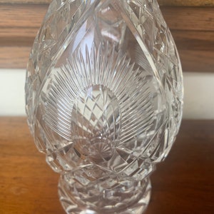 May include: A clear glass decanter with a cut crystal design. The decanter has a round body and a wide base.