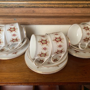 Peut inclure: Ensemble de trois tasses à thé et soucoupes blanches avec un motif floral or et bordeaux.