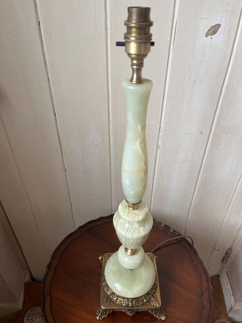 Peut inclure: Une lampe de table vintage avec un corps en onyx vert clair et des accents en laiton. La lampe a une base carr&eacute;e avec des d&eacute;tails orn&eacute;s et une douille en haut. La lampe mesure environ 51 cm de haut.