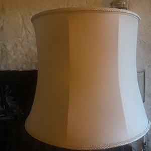 May include: A white lampshade with a pleated design and a rope trim around the top and bottom.