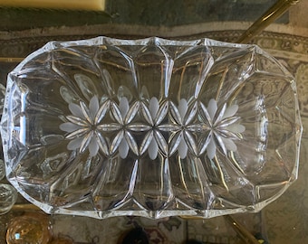 May include: A clear glass serving dish with a decorative etched pattern of flowers. The dish has a rectangular shape with rounded edges.