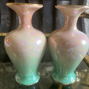 Puede incluir: Dos jarrones de cerámica iridiscente con un esmalte degradado rosa y verde. Los jarrones tienen un borde dorado y una parte superior acampanada.