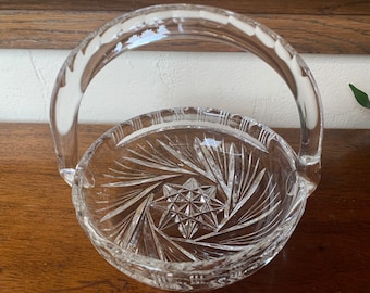 Könnte beinhalten: Eine klare Glasschüssel mit geschnittenem Glasdesign und einem Griff. Die Schüssel hat ein sternförmiges Design in der Mitte.