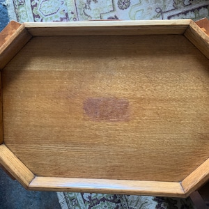 Può includere: Vassoio di legno da portata di forma ottagonale. Il vassoio è realizzato in legno chiaro con venature visibili. Ha due manici con un materiale chiaro simile alla pietra. Il vassoio è progettato per servire cibo o bevande.