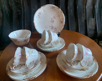May include: A set of vintage floral teacups and saucers with gold trim. The set includes a teapot, sugar bowl, and creamer.