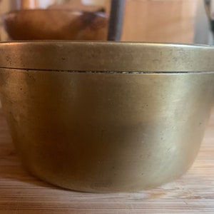 May include: A brass bowl with a slightly flared rim. The bowl has a smooth, polished surface with a subtle sheen.