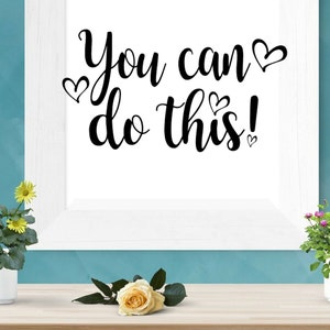 Può includere: Stampa incorniciata bianca con il testo "You can do this!" in lettere corsive nere con piccoli cuori intorno al testo.