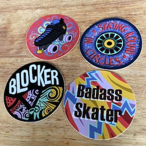 以下が含まれることがあります： 異なるデザインの丸いステッカーが4つあります。1つのステッカーは、白い渦巻きのある赤い背景に、青い車輪が付いた黒いローラースケートが描かれています。もう1つのステッカーは、白いドットのある濃い青色の背景に、赤い円の中に青い目と黄色の目が描かれています。3つ目のステッカーは、カラフルなデザインと「BLOCKER」という文字が書かれた黒い背景です。4つ目のステッカーは、黄色、赤、紫の背景に稲妻のデザインと「Badass Skater」という文字が書かれています。
