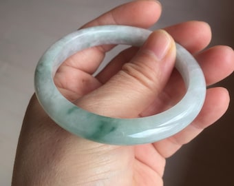 May include: A light green jade bangle bracelet with a smooth, polished finish.
