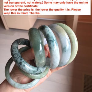 May include: A collection of jadeite jade bangles in various sizes and shades of green. The bangles have visible imperfections, including cracks, color roots, and dark spots.