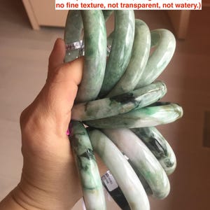 May include: A stack of jadeite jade bangles in various sizes. The bangles are green with white and black markings.  Jadeite Jade Bangles. Variety of sizes. With this low price, they all have defects (could be cracks, hairlines, color roots, dark spots, black areas, rough surfaces, no fine texture, not transparent, not watery.) Please read the whole item description before you order. Thanks