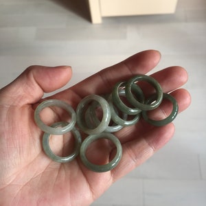 Könnte beinhalten: Eine Sammlung von Jade-Ringen in verschiedenen Grüntönen, gestapelt und in einer Hand angeordnet.