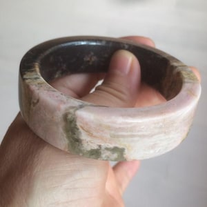 Può includere: Un braccialetto in pietra rosa e marrone con una finitura liscia e lucida.