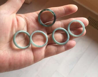 May include: Five jade rings in various shades of green, with one ring having a darker green band.