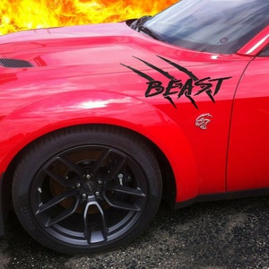 May include: A red Dodge Challenger with black racing stripes and the word "BEAST" on the side. The car has black wheels and a black hood scoop.