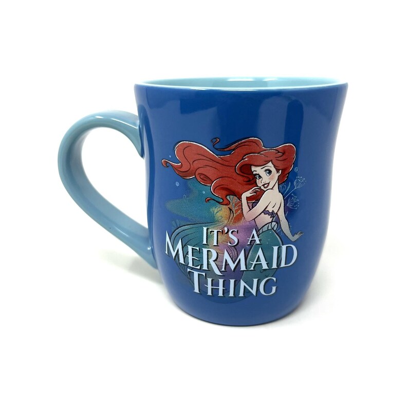 Pu&ograve; includere: Tazza in ceramica blu con Ariel de La Sirenetta. La tazza ha un manico e un interno azzurro. La parte anteriore della tazza mostra Ariel con la scritta "It's a Mermaid Thing."