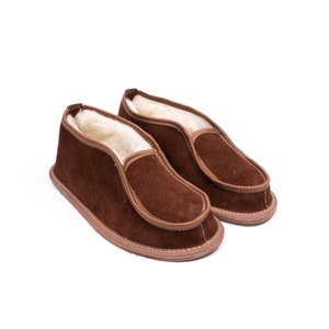 May include: A pair of brown suede slippers with a sheepskin lining. The slippers have a simple design and are perfect for keeping your feet warm in the winter.