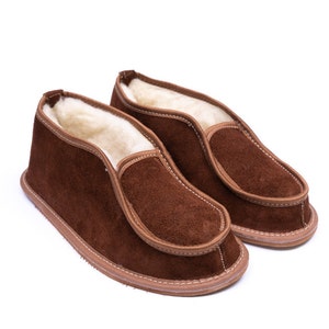 May include: A pair of brown suede slippers with a soft, fuzzy lining. The slippers have a simple, slip-on design and a comfortable fit.