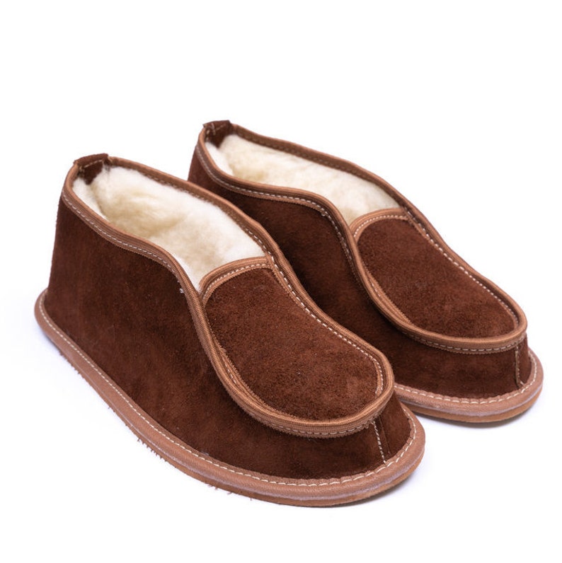 May include: A pair of brown suede slippers with a soft, fuzzy lining. The slippers have a simple, slip-on design and a comfortable fit.