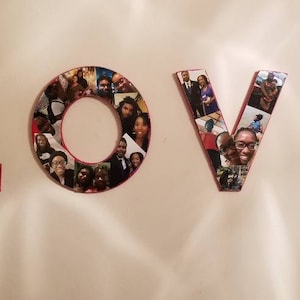 Pu&ograve; includere: La parola "LOVE" esposta su un muro, ogni lettera costruita da singole fotografie. Le lettere hanno un bordo rosso e le foto presentano varie persone. Le lettere sono montate su un muro di colore chiaro.