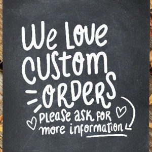 Può includere: Un cartello nero in ardesia con testo bianco che dice "We love custom orders. Please ask for more information." Ci sono due piccoli cuori disegnati sul cartello.