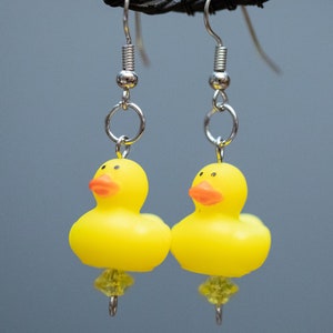 May include: A pair of yellow rubber ducky earrings with silver hooks and clear crystal accents.