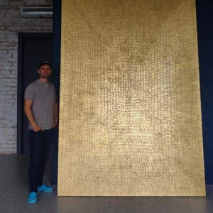 May include: A large, abstract painting with a textured, gold surface. The painting is made up of small, individual shapes that create a swirling, radial pattern.