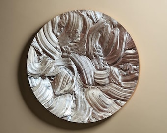 May include: A round, white and brown wall decor with a textured, abstract design. The decor has a circular shape and is made of a textured material.