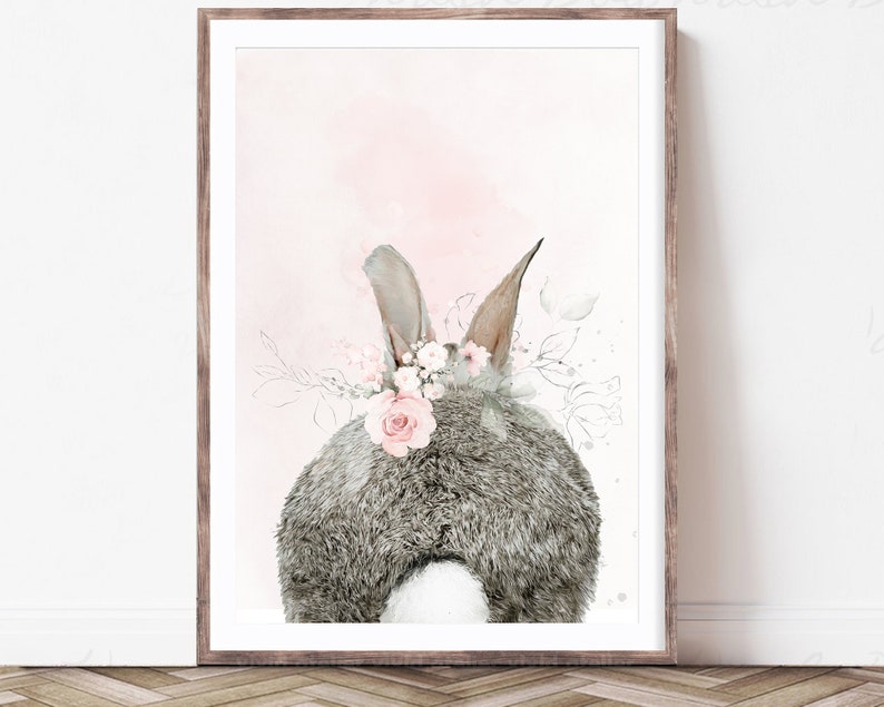 Puede incluir: Una pintura de acuarela de un conejo gris con una corona de flores rosas. El conejo est&aacute; de espaldas al espectador y el fondo es de color rosa suave.