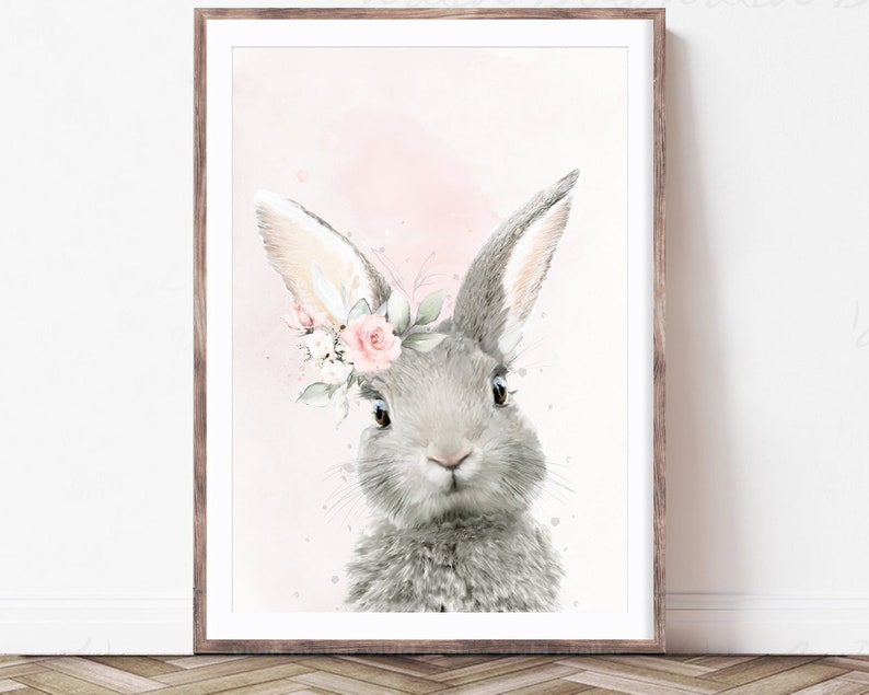 Puede incluir: Una pintura de acuarela de un conejo gris con flores rosas en su pelaje. El conejo est&aacute; mirando al espectador con grandes ojos marrones. El fondo es de un rosa suave.