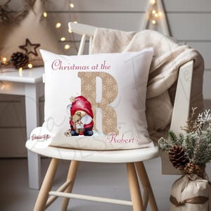 May include: White cushion with a red and white gnome holding a teddy bear. The cushion has a gold glitter letter R and the text "Christmas at the Robert's".