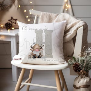 May include: White cushion with a silver glitter letter H and a cartoon reindeer wearing a Santa hat. The cushion reads "Christmas at the Harrison's".