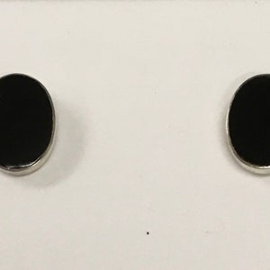 May include: A pair of silver oval stud earrings with black onyx stones.