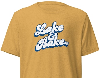 May include: A mustard yellow t-shirt with a white and blue retro-style graphic that says "Lake & Bake".