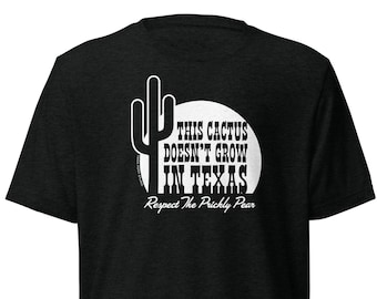 May include: A black t-shirt with a white cactus graphic and the text "THIS CACTUS DOESN'T GROW IN TEXAS Respect The Prickly Pear". The shirt is made of a soft, comfortable material.