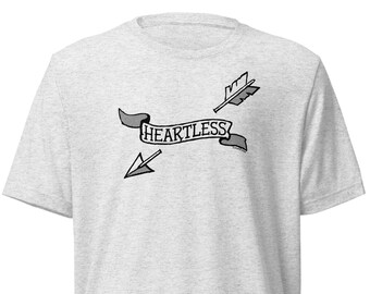 May include: A heather gray t-shirt with a black and white graphic of a banner with the word "HEARTLESS" and two arrows.