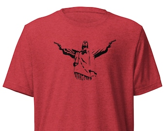 May include: Red t-shirt featuring a black graphic of a figure with outstretched arms holding two guns. The graphic is a silhouette style. The shirt has a crew neck and short sleeves.