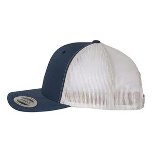 May include: A navy blue and white trucker hat. The front panels and brim are navy blue, while the back is white mesh. The hat has a curved brim and a snapback closure. The hat has a small, circular logo on the front.