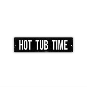 May include: A rectangular black metal sign with the words "HOT TUB TIME" in white, uppercase letters. The sign has a distressed, vintage appearance and is mounted on a white background.
